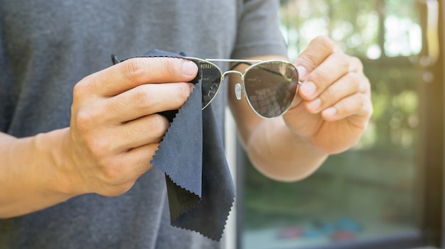 Männer halten und säubern eine Sonnenbrille.