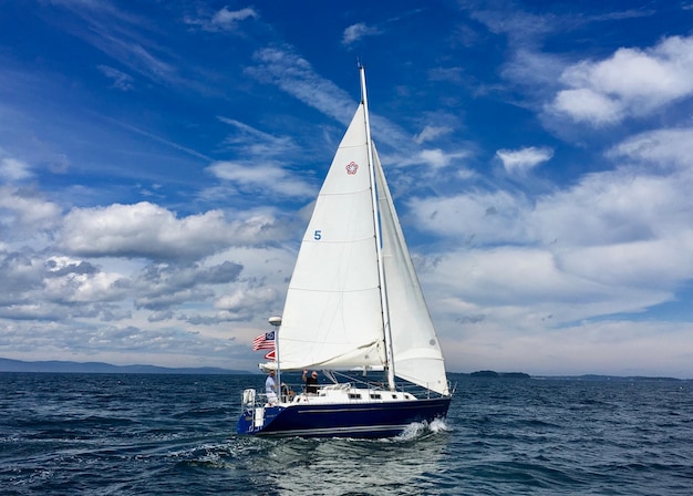 Männer im Segelboot auf See gegen den blauen Himmel