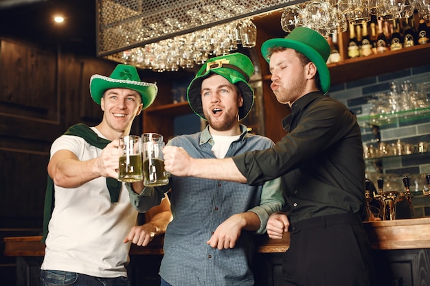 Männer in grünen Hüten. Freunde feiern den St. Patrick's Day. Feier in einer Kneipe.