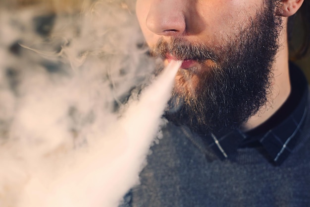 Männer mit Bart dampfen und setzen eine Dampfwolke aus der Nähe frei