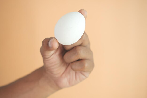Männer mit einem weißen Ei vor einem orangefarbenen Hintergrund