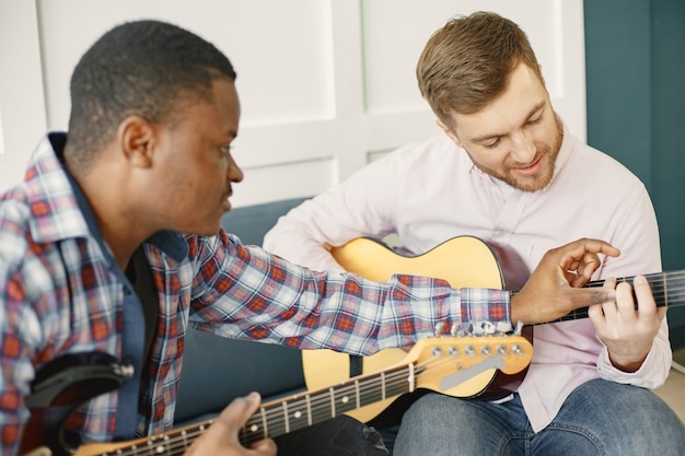 Männer spielen Gitarre. Musik komponieren. Afrikanische und kaukasische Männer.