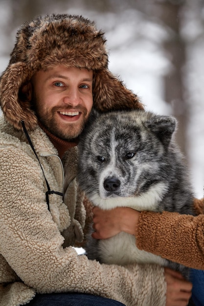 Männer spielen mit sibirischem Husky im Winterwald und parken Tiere und Ökologie