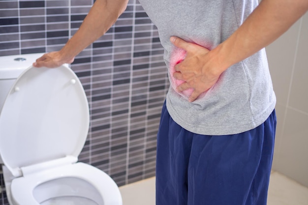 Männer stehen mit dem Bauch vor der Toilette im Badezimmer