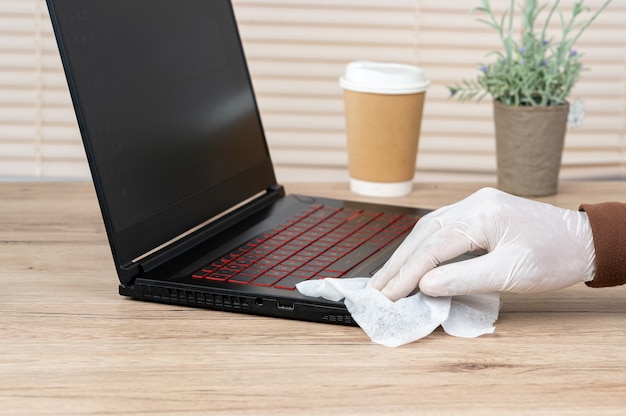 Männer tragen weiße Handschuhe, reinigen ihre Laptops mit Alkohol und Spay-Tüchern, um Viren vorzubeugen.