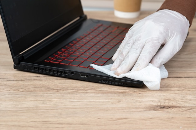 Männer tragen weiße Handschuhe, reinigen ihre Laptops mit Alkohol und Spay-Tüchern, um Viren vorzubeugen.