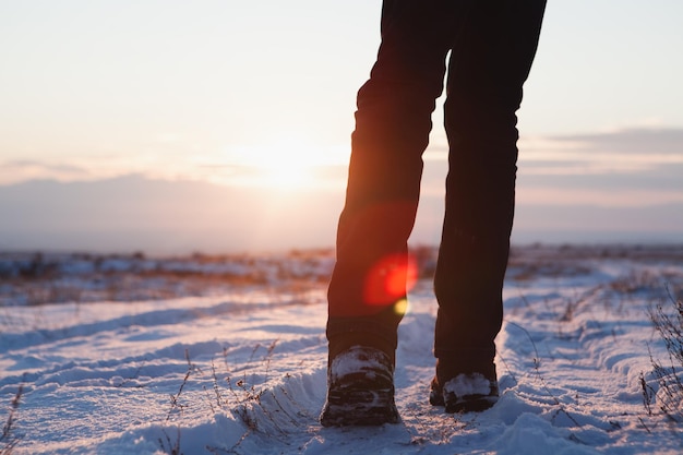 Männerfüße in Stiefeln im Schnee, die im Winter gehen