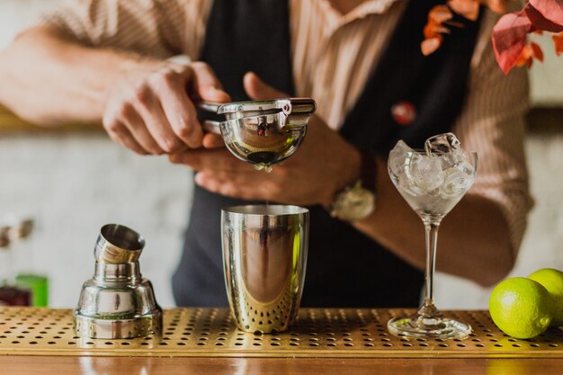 Männerhände drückten Limettensaft in einen Shaker an der Bar. Selektiver Fokus, natürliches Licht.