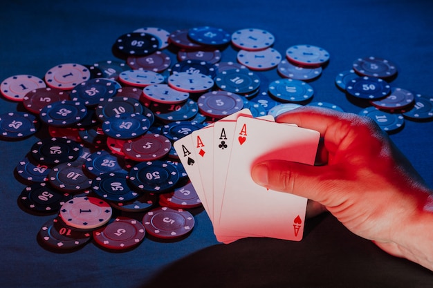 Männerhände halten Karten auf dem Hintergrund des Spielens von Pokerchips