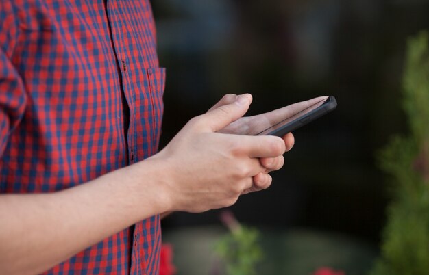 Männerhände mit mobilem Smartphone im Freien