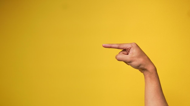 Männerhand mit zeigender Geste auf gelbem Hintergrund