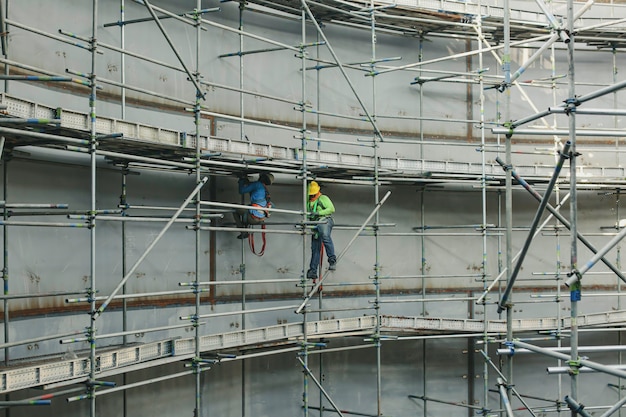 Männliche Arbeiter des Baus tanken Öl, das Gerüste im Seitentank installiert, begrenzte Spezifikation