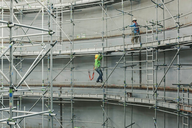 Männliche Arbeiter des Baus tanken Öl, das Gerüste im Seitentank installiert, begrenzte Spezifikation