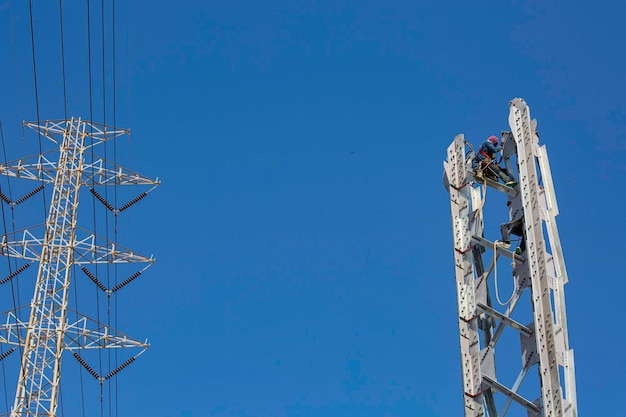 Männliche Arbeiter Installation von Hochspannungs-Strommasten die Online-Säulenstahlarbeiten bei Höhenrisiko