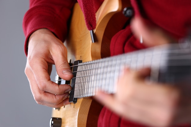 Männliche Arme, die E-Gitarre der klassischen Form spielen