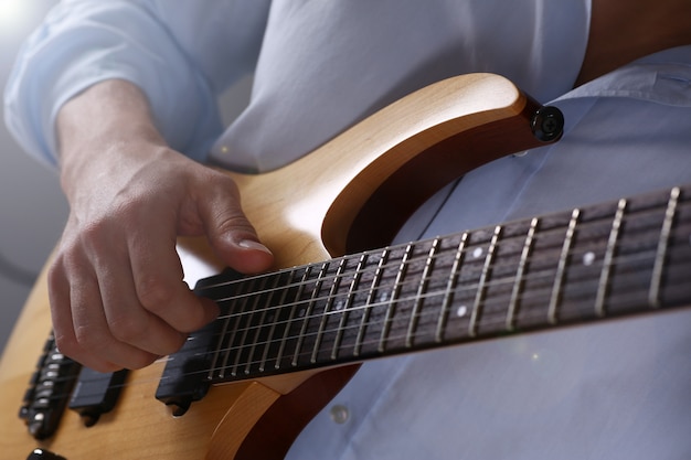 Männliche Arme halten und spielen klassische Form Holz-E-Gitarren-Nahaufnahme.