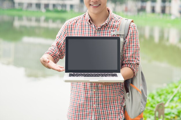 Männliche asiatische Hand, die draußen Laptopbildschirm zeigt