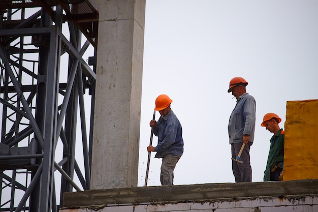 Männliche Bauherren arbeiten am Bau eines mehrstöckigen Zementgebäudes