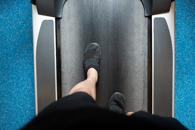 Männliche Beine, die auf Tretmühle in der Turnhalle gehen und laufen. Cardio-Training ausüben