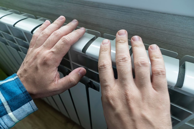 männliche Berührung kaum warme Batterie während der Heizzeit Heizgeräte im Haus Seitenansicht Unbehagen durch die Kälte