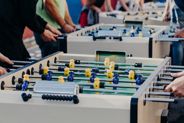 Männliche Freunde spielen Tischfußball mit großer Hitze genießen Erholungszeit oder Freizeit wollen gewinnen Unterhaltungszentrum Bunte Plastikspieler beim Fußballspiel