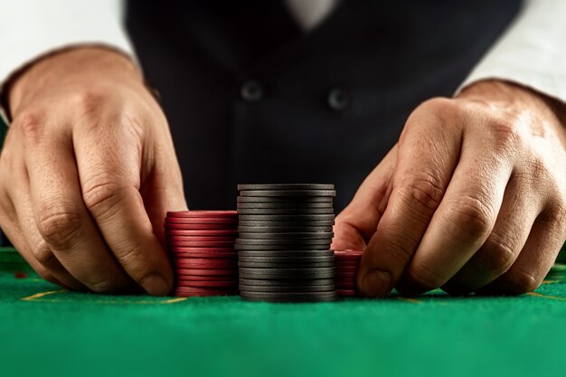 Männliche Hände croupier in einem Kasino und spielen Chips auf einer grünen Stoffnahaufnahme