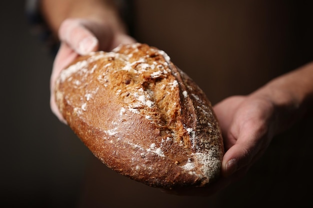 Männliche Hände, die frisch gebackenes Roggenbrot in der Nähe halten