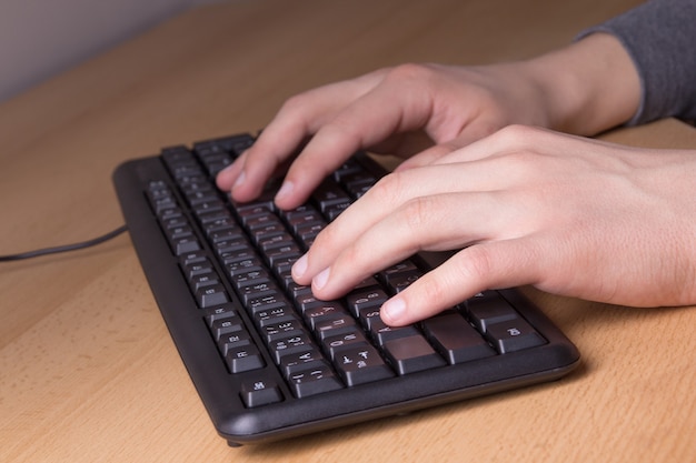 Männliche Hände, die mit PC-Tastatur arbeiten