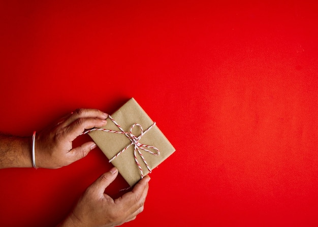 Männliche Hände, die rote Geschenkbox halten