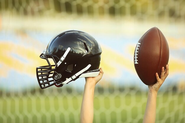 Männliche Hände, die Rugby-Helm und Ball halten