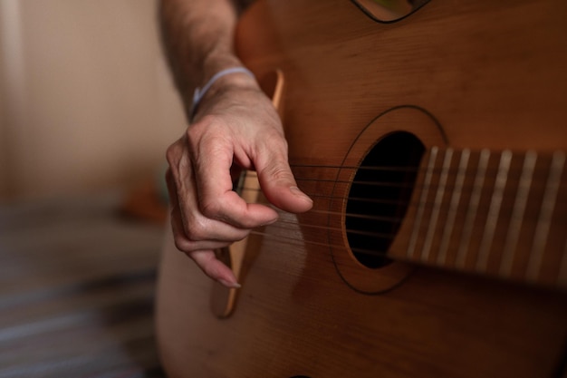 Männliche hände eines älteren kaukasischen mannes, der eine klassische gitarre hält und spielt, schließen zu hause unprofessionelle gesichtslose gitarristenleute spielen amateurmusik, häusliche hobbys und freizeit