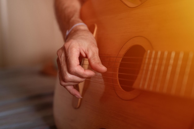 Männliche hände eines älteren kaukasischen mannes, der eine klassische gitarre hält und spielt, schließen zu hause unprofessionelle gesichtslose gitarristenleute spielen amateurmusik, häusliche hobbys und freizeitaufflackern