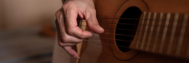 Männliche hände eines älteren kaukasischen mannes, der eine klassische gitarre hält und spielt, schließen zu hause unprofessionelle gesichtslose gitarristenleute spielen amateurmusik häusliche hobbys und freizeitbanner