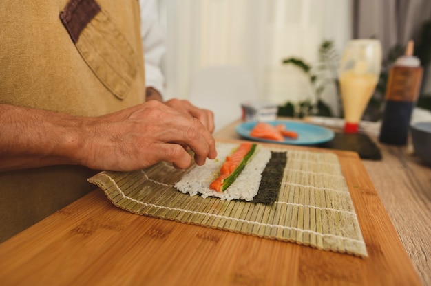 Männliche Hände hautnah rollende Sushi-Rollen mit Bambusmatte
