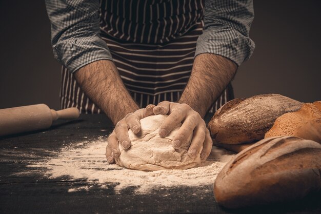 Männliche Hände kneten den Teig. Koch kocht Brot und Brötchen