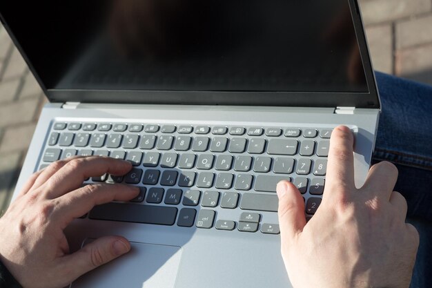 Männliche Hände Laptop-Tastatur Tippen von Text das Konzept einer Freiberufler Arbeit in der frischen Luft