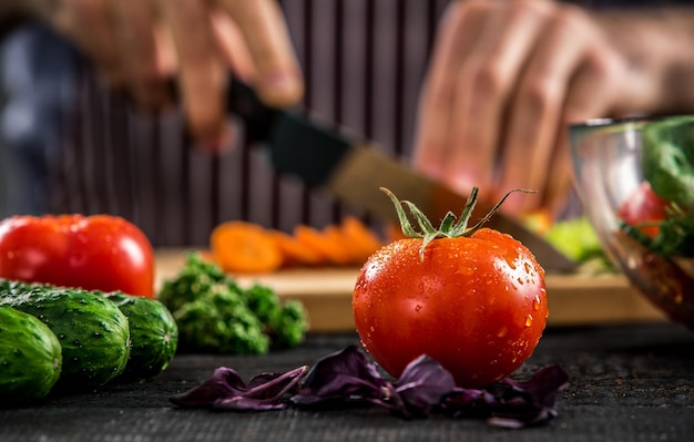 Männliche Hände schneiden Gemüse für Salat