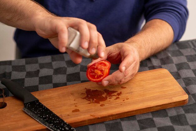 Foto männliche hände schneiden tomaten auf einem brett