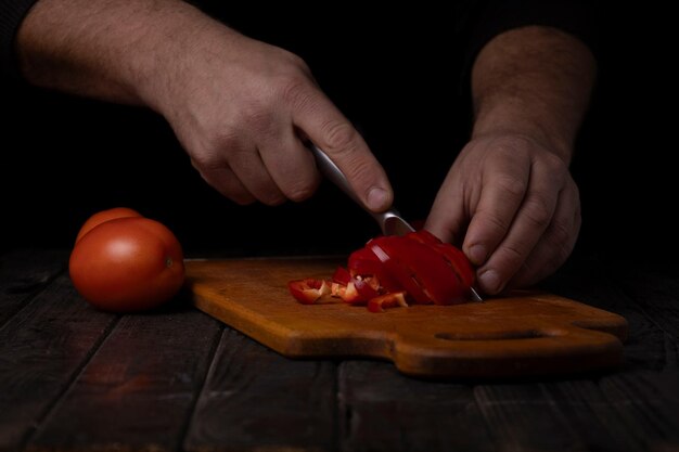 Foto männliche hände schneiden tomaten auf einem schneidbrett