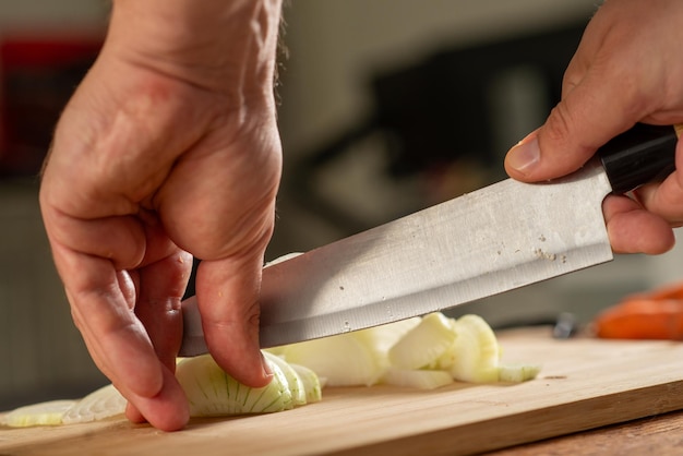 Männliche Hände schneiden Zwiebeln in der Küche