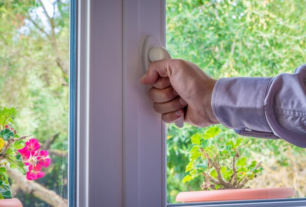 Männliche Hand am Griff eines Fensters