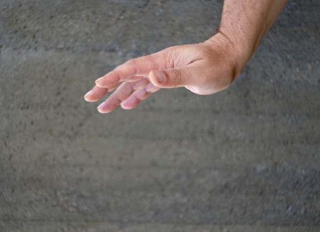 Männliche Hand auf einem grauen monophonen Hintergrund in einer willkommenen oder negativen Geste