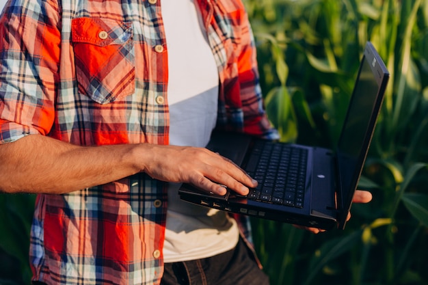 Foto männliche hand der nahaufnahme auf dem laptop. landwirt, der auf einem gebiet hält offenes notizbuch steht.