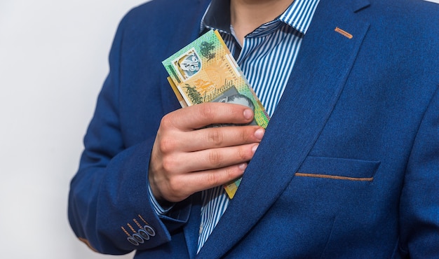 Männliche Hand, die australische Dollarbanknoten in der Tasche versteckt