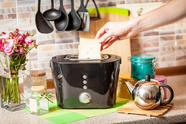 Männliche Hand, die gebackenen Toast aus dem Toaster nimmt