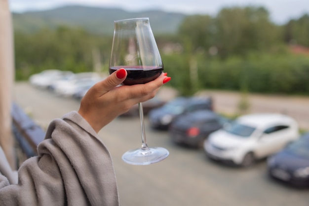 Männliche Hand, die Glas mit Wein auf unscharfem natürlichem Hintergrund hält.