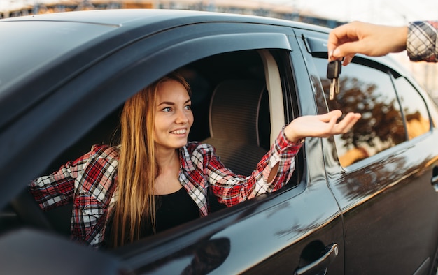 Männliche Hand gibt die Autoschlüssel an weibliche Fahrerin