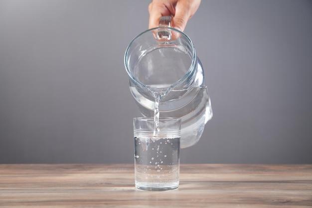 Männliche Hand gießt Wasser in Glas Gesundes Getränk