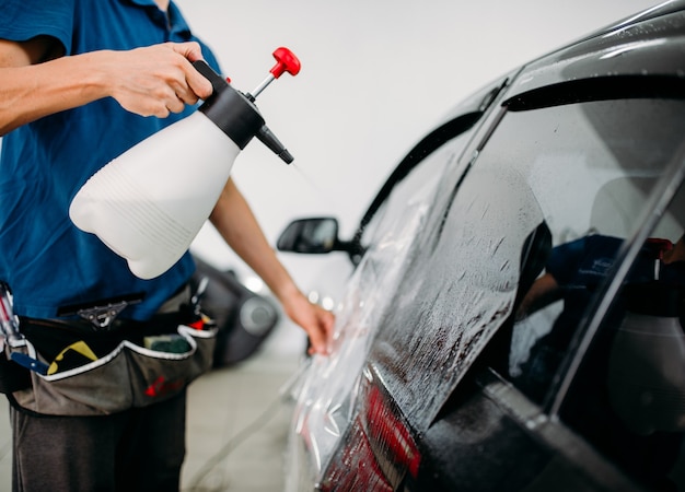 Männliche Hand mit Spray, Autofenstertönungsinstallation