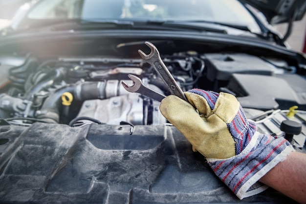 Männliche Hand mit Stahlschlüsseln am Automotor